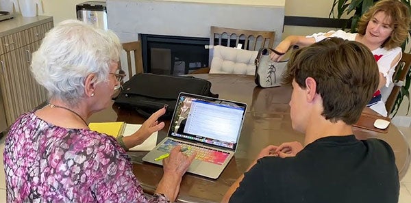 teen helping older woman with computer