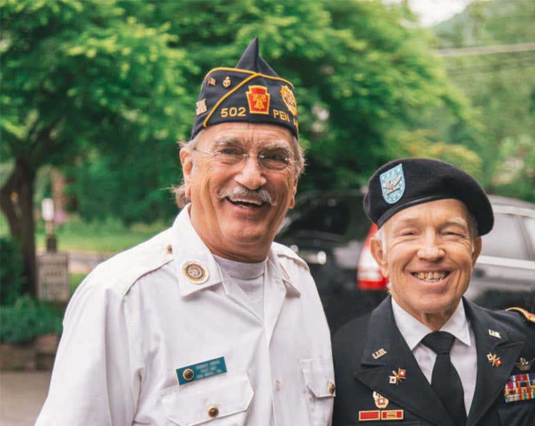 Two senior male veterans smile for the camera.