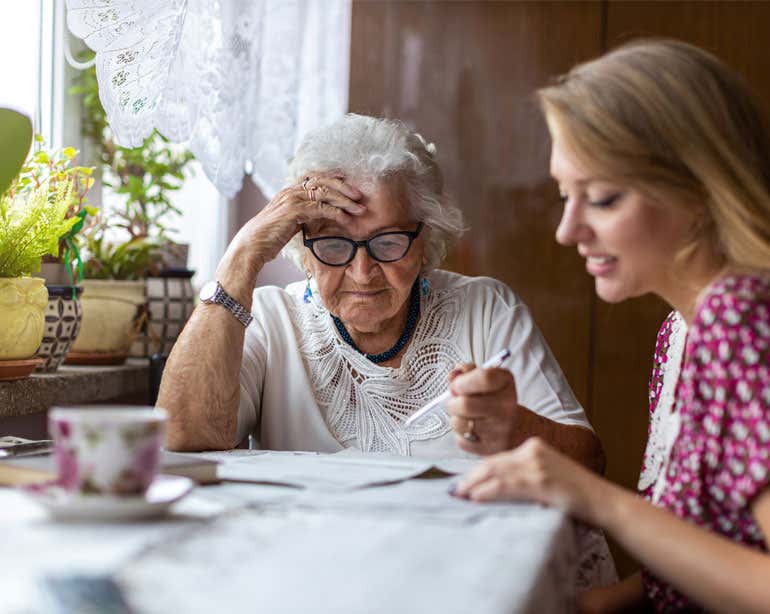 A young female caregiver helps her grandmother with her financial paperwork.