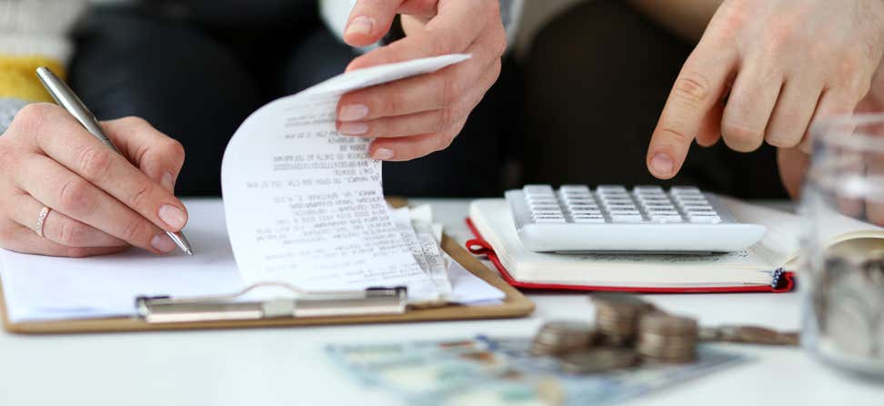 Two people are looking over receipts and other financial paperwork as they work to balance their household budget.