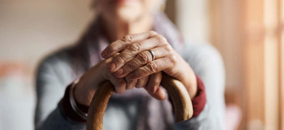 A closeup shot of a senior woman holding her cane in a senior center.