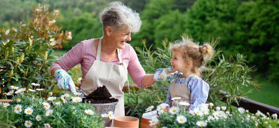 A senior Caucasian woman is out in her garden with her granddaughter.