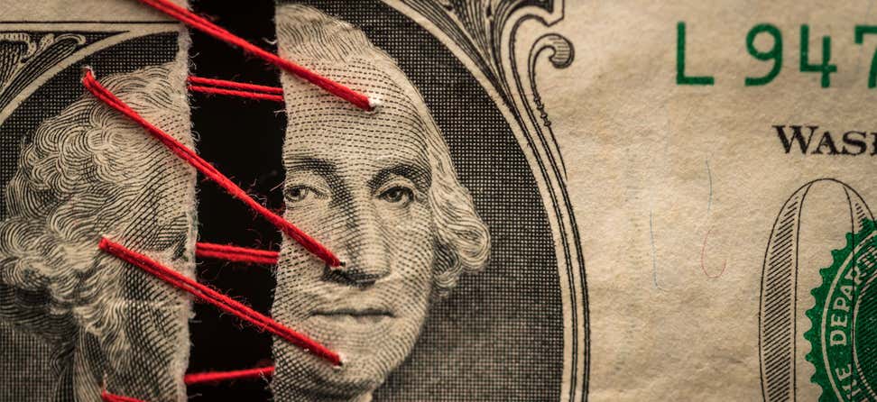 An up-close shot of a dollar bill being stitched together with red thread at George Washington's face.