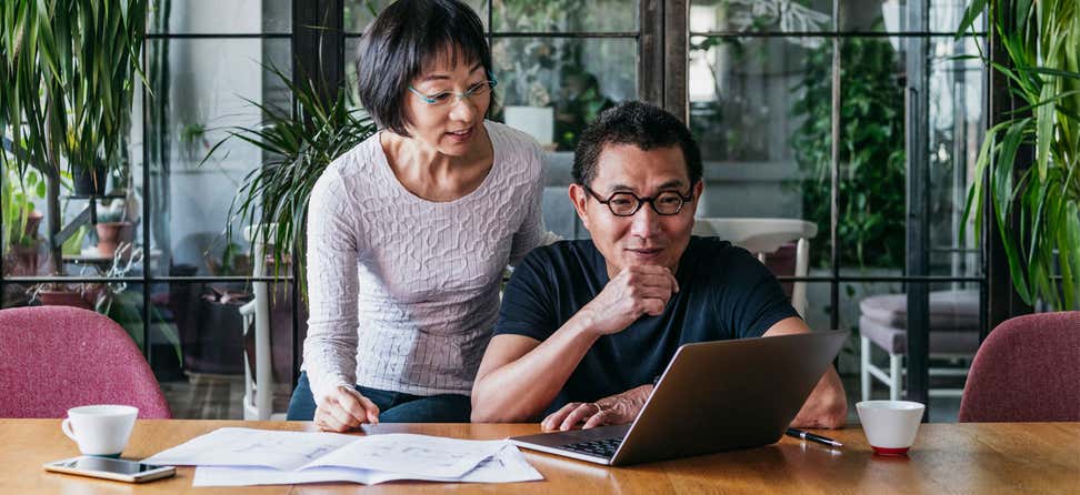 An older Asian couple is contemplating financial decisions over coffee.