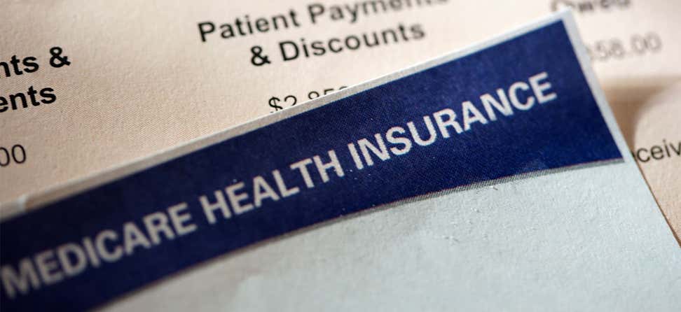 Closeup shot of a hospital bill alongside a Medicare enrollment form.