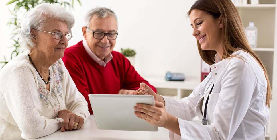 Older Caucasian couple reviewing medical information with doctor on a tablet.