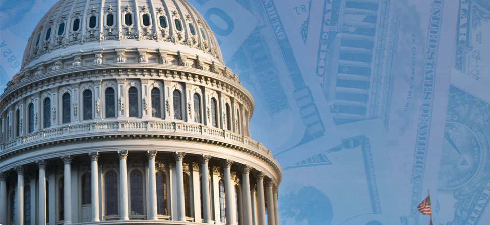 A shot of the U.S. Capitol dome overlaid on top of a background of one-hundred dollar bills.