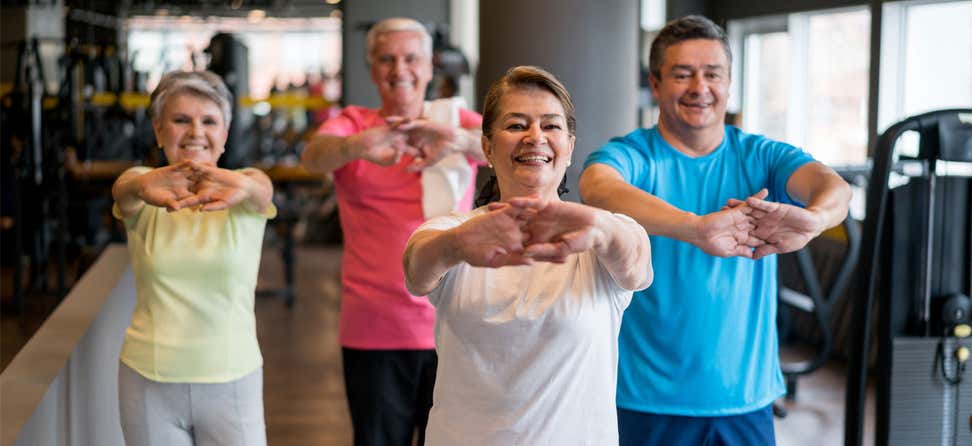 A group of Hispanic older adults are exercising together, doing stretching exercises.