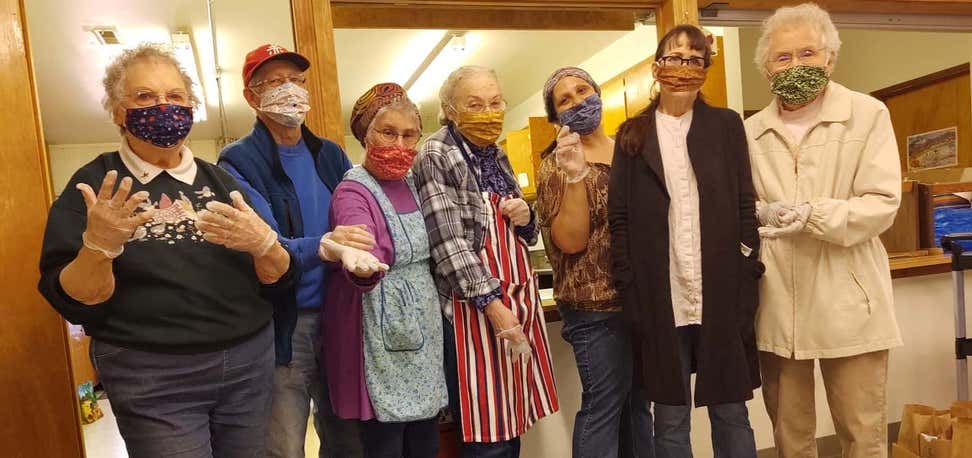 Seven older adults wearing masks in community center.