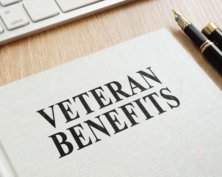 A book on a desk reads "VETERANS BENEFITS" in all caps.