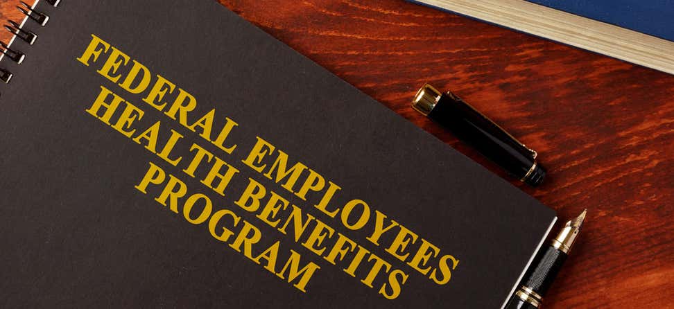 A close up shot of a handbook with the words "Federal Employees Health Benefits Program" on the face.