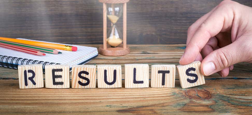 An older man uses Scrabble pieces to spell out the word "RESULTS".