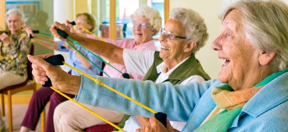 A group of seniors are doing stretch band exercises together at a senior center.