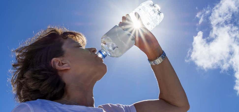 Woman, senior, drinking water in the sunlight, back lit image with sunbeams