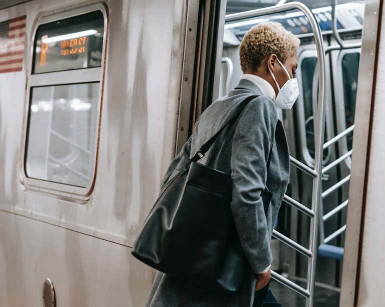 An older Black professional woman is seen getting on the subway.