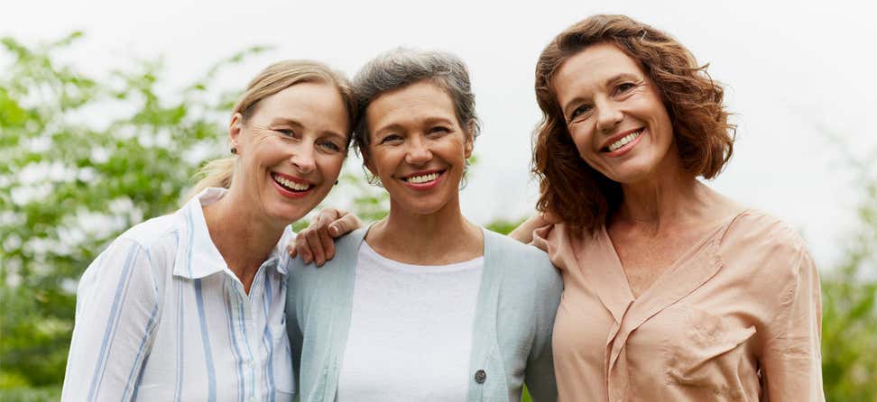 Three older women are outside posing for the camera, smiling.