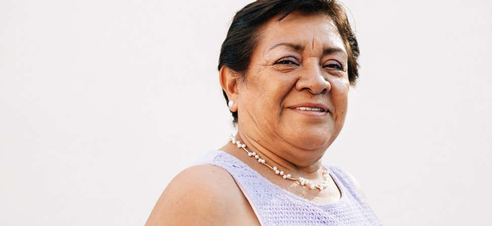 A senior Mexican woman living with obesity smiles at the camera, being an advocate for her obesity care options.