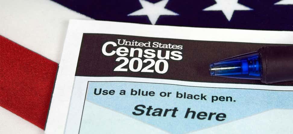 A close up shot of a U.S. Census 2020 form with a U.S. flag as the backdrop. 