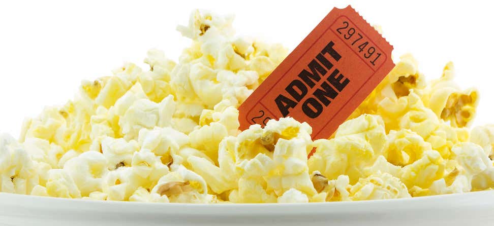 An up close shot of a bucket of popcorn and a ticket that says "Admit One".