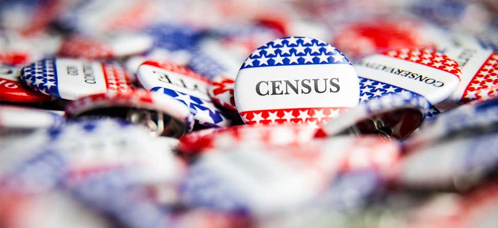 A pile of red, white, and blue political buttons with one facing the camera that reads "CENSUS" .