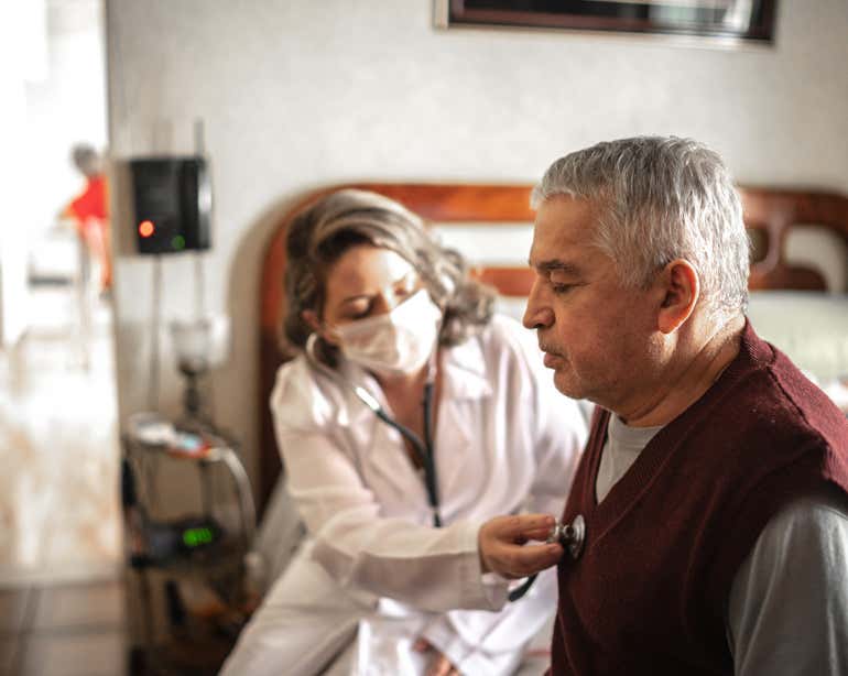A nurse is listening to the heartbeat of a Hispanic senior man.