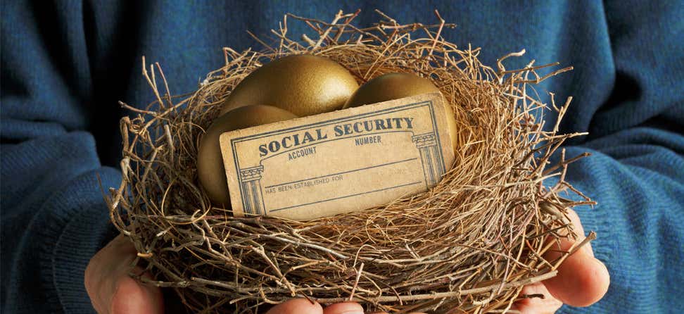 An older man holds a nest that contains two golden eggs and a blank social security card.