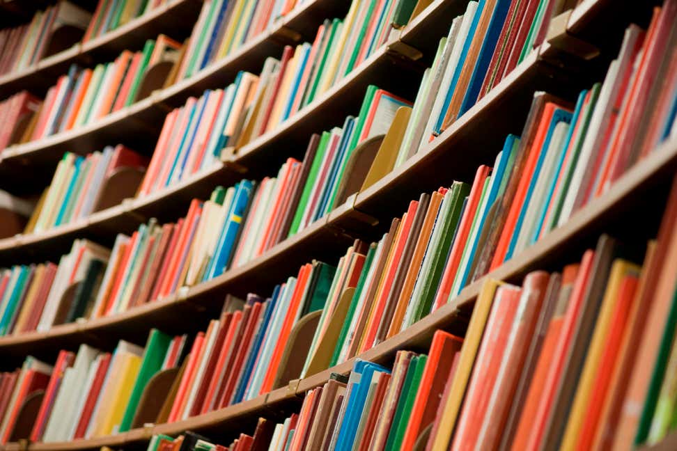 A photo of a library's shelves with many colorful books.