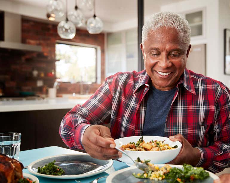 A Black senior man is enjoying a healthy meal at home in his kitchen.