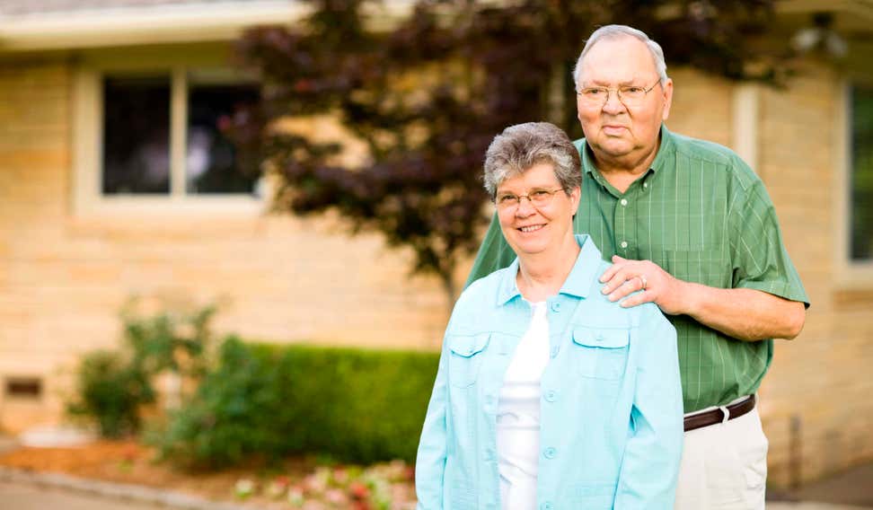 Senior couple standing outside their house