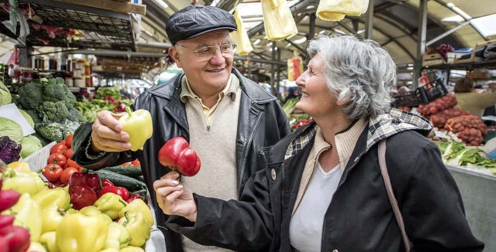 Smiling senior couple buying vegetables together at a farmer's market.
