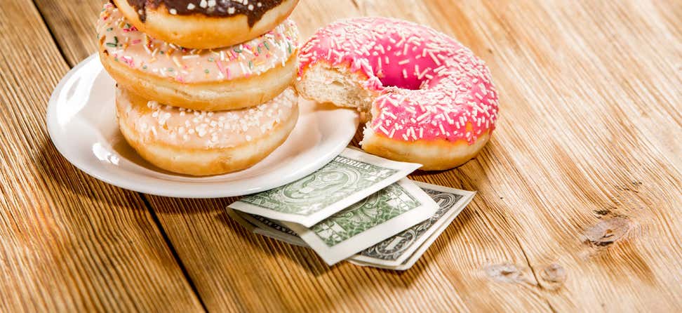 Three donuts stacked on a plate on top of money.