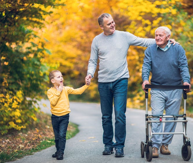 An older man and his adult son and grandson go out for a walk in the park.