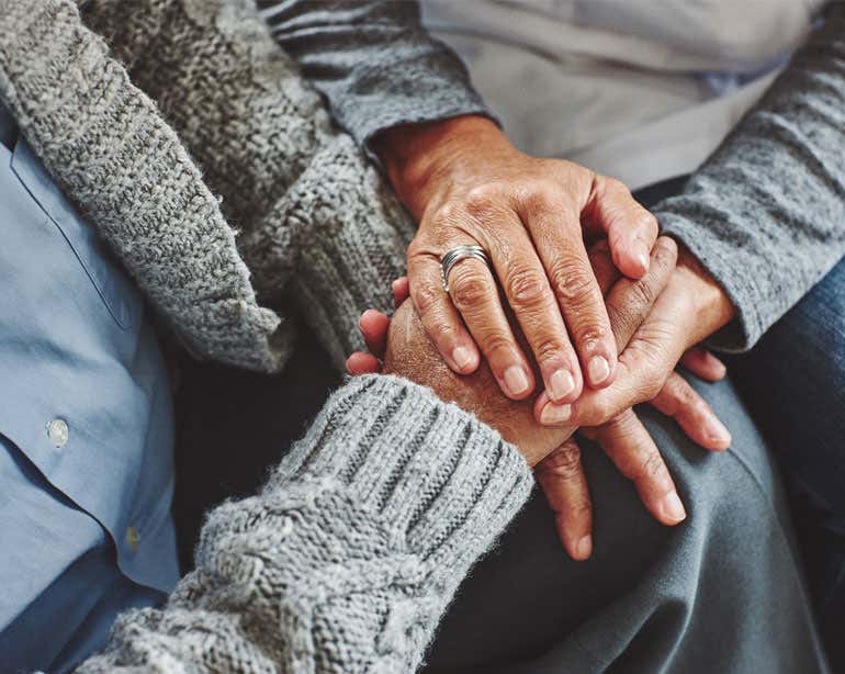 Close up shot of a senior Black couple holding hands.