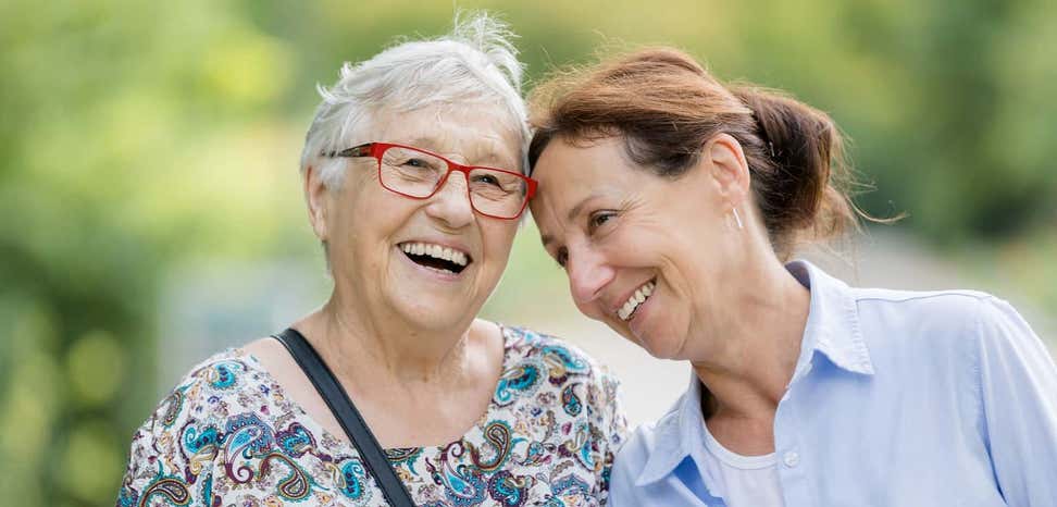 Two happy older women take a walk outside together.